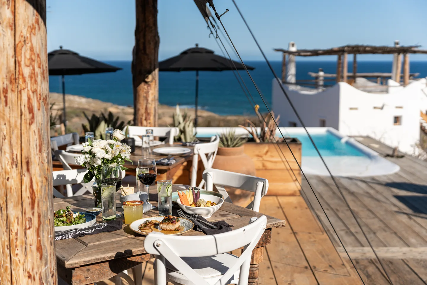Restaurant terrace set for lunch beside the pool and the sea — NEST Baja