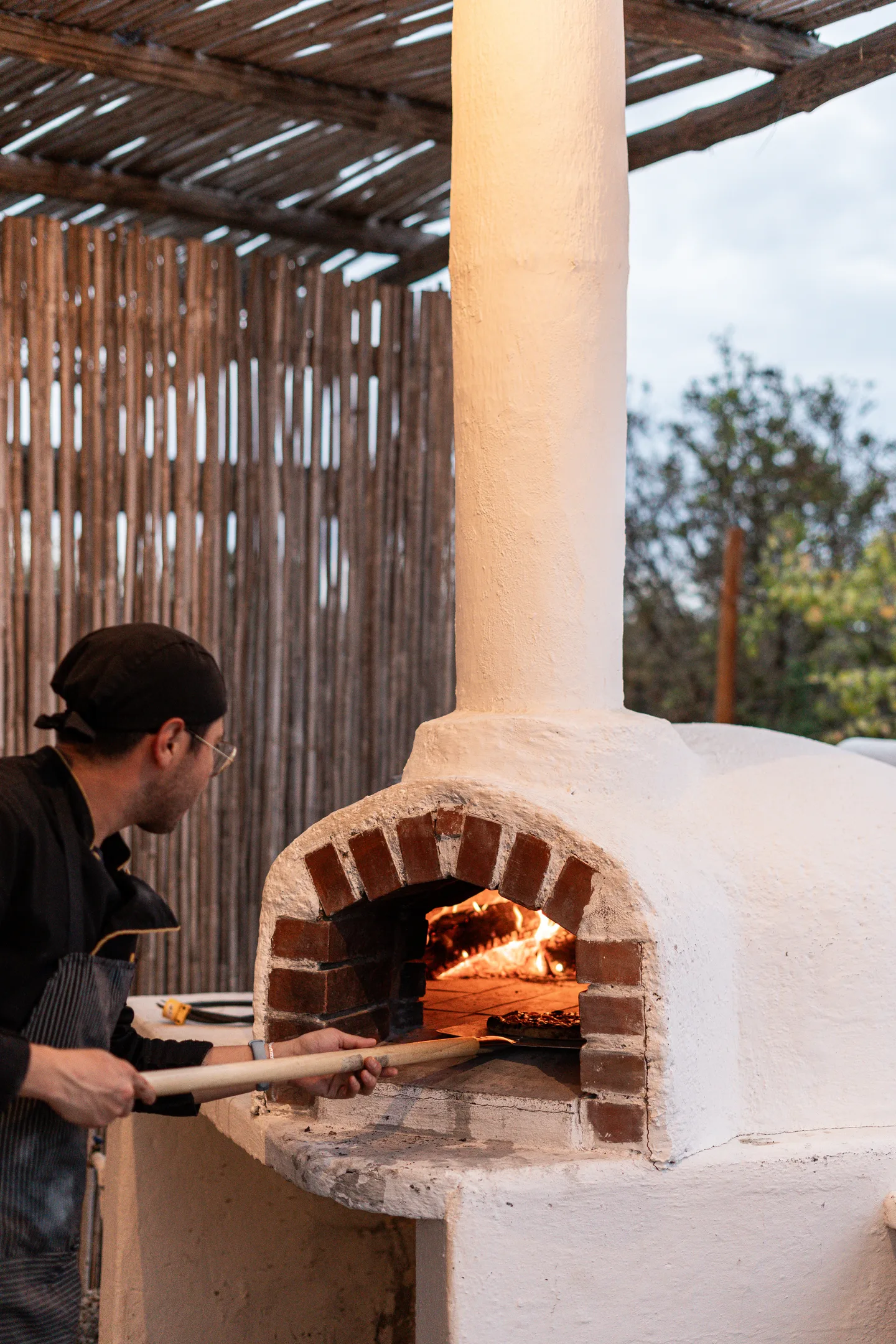 Chef junto al horno de leña para pizza — NEST Baja