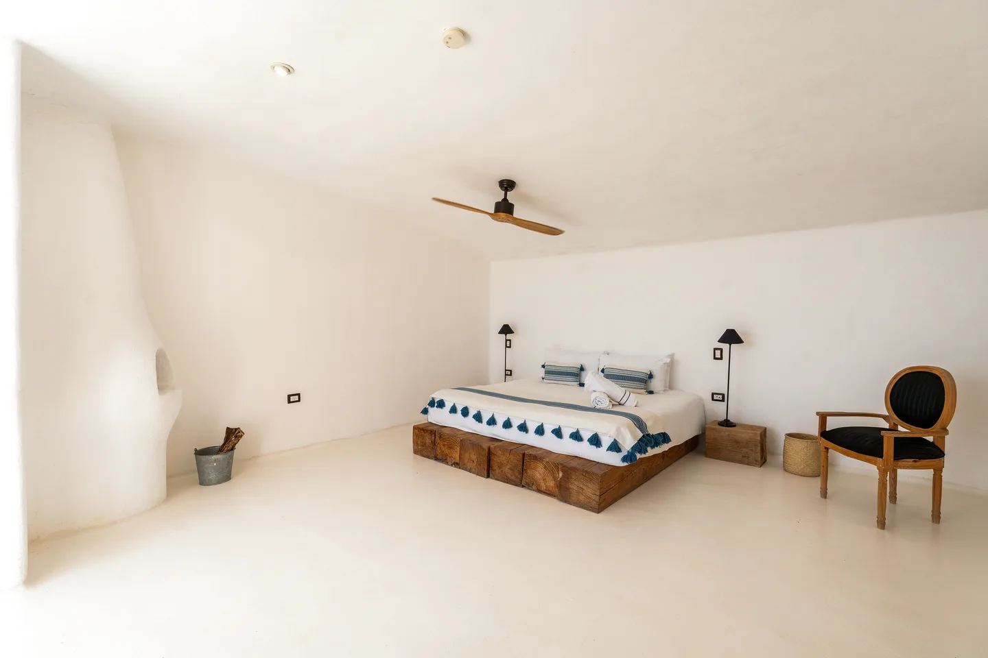 King bed on a raw timber base in the vaulted white master bedroom — NEST Baja
