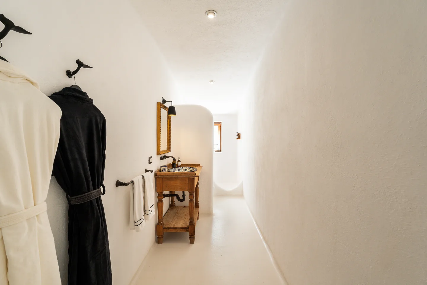 Bathroom corridor with bathrobes and wooden vanity — NEST Baja