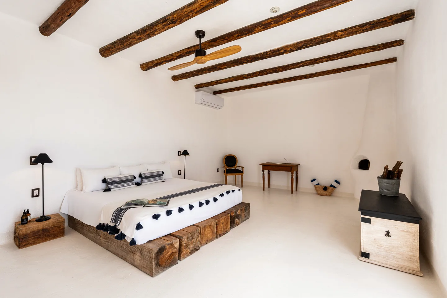 Cama king sobre base de madera natural bajo vigas rústicas — NEST Baja
