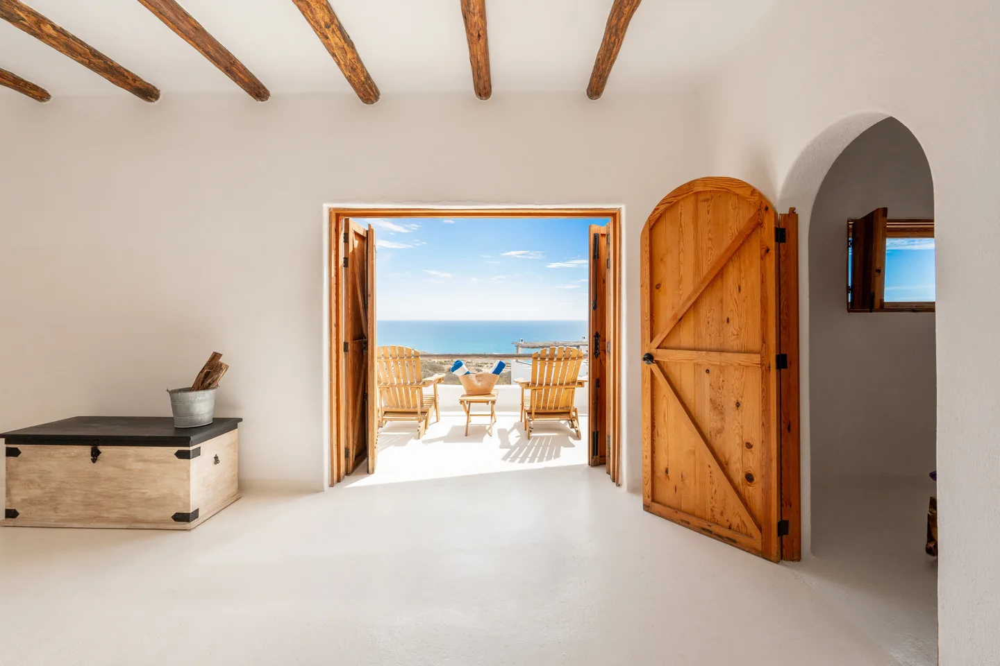 Puerta de granero arqueada y entrada enmarcando la terraza y el mar — NEST Baja