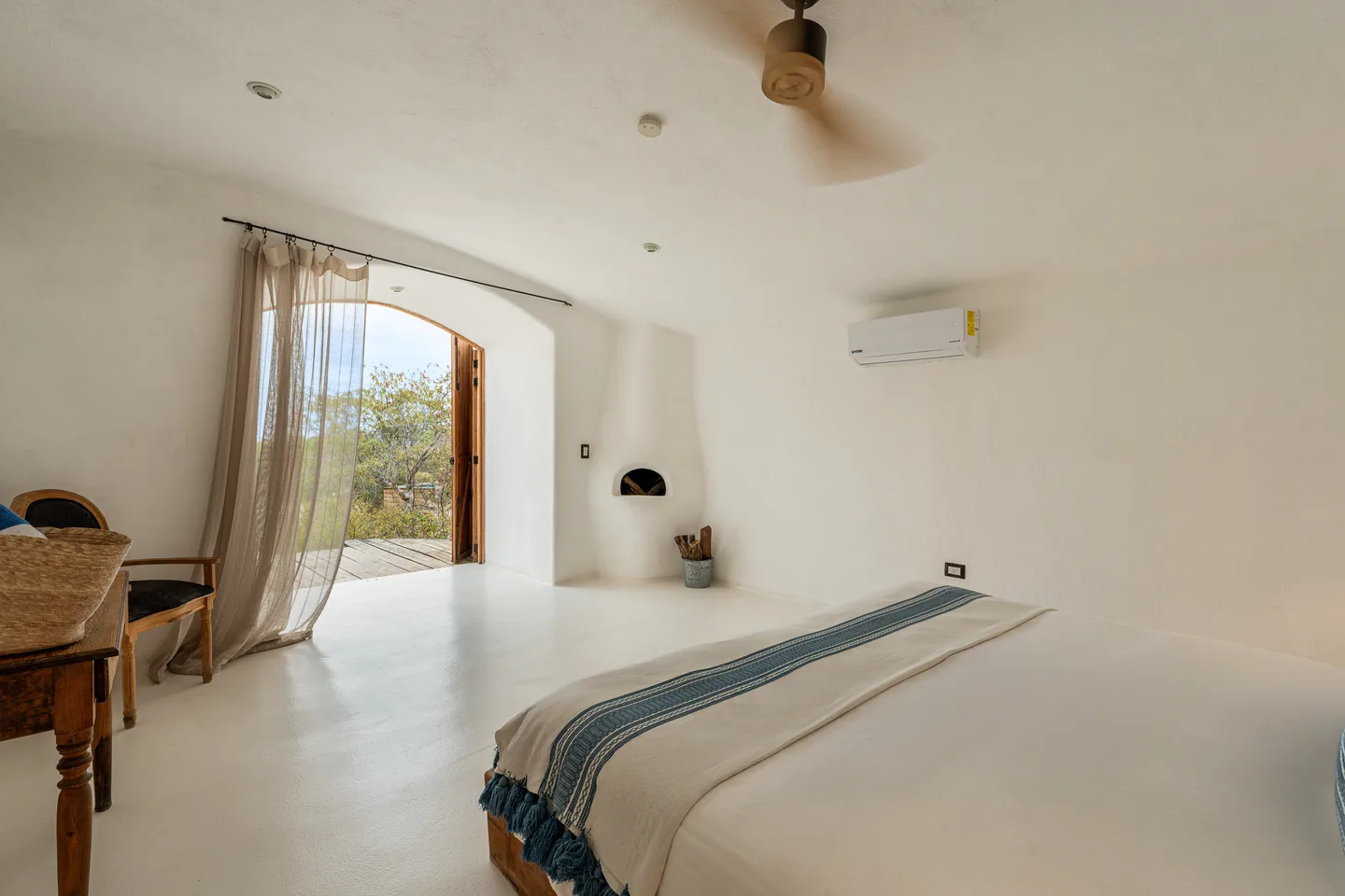 Habitación abovedada con chimenea y puerta de arco hacia la terraza — NEST Baja
