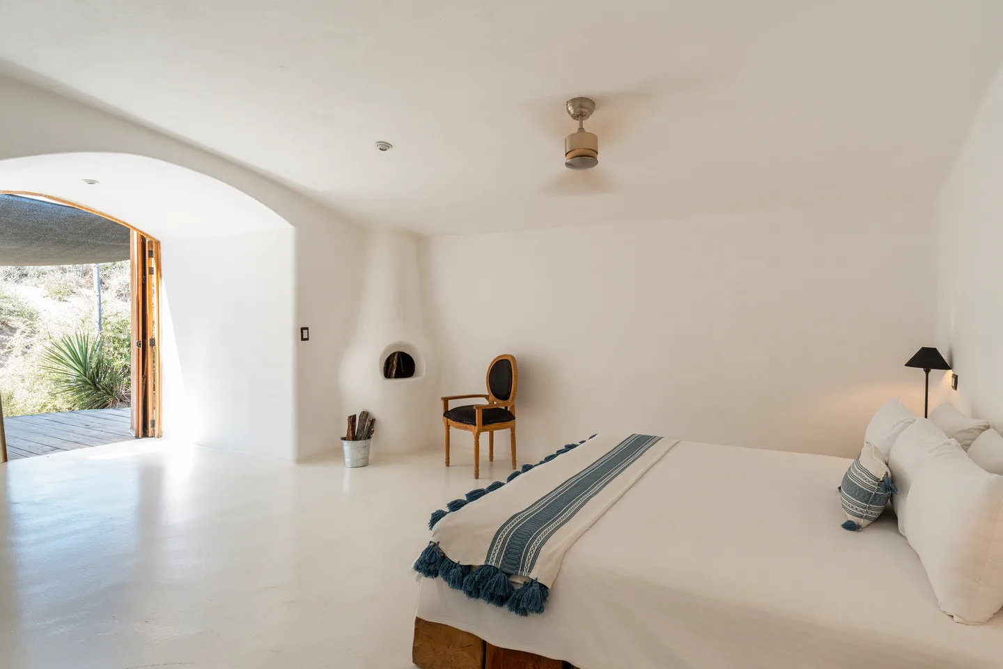 Recámara con chimenea azteca y puerta en arco hacia la terraza — NEST Baja