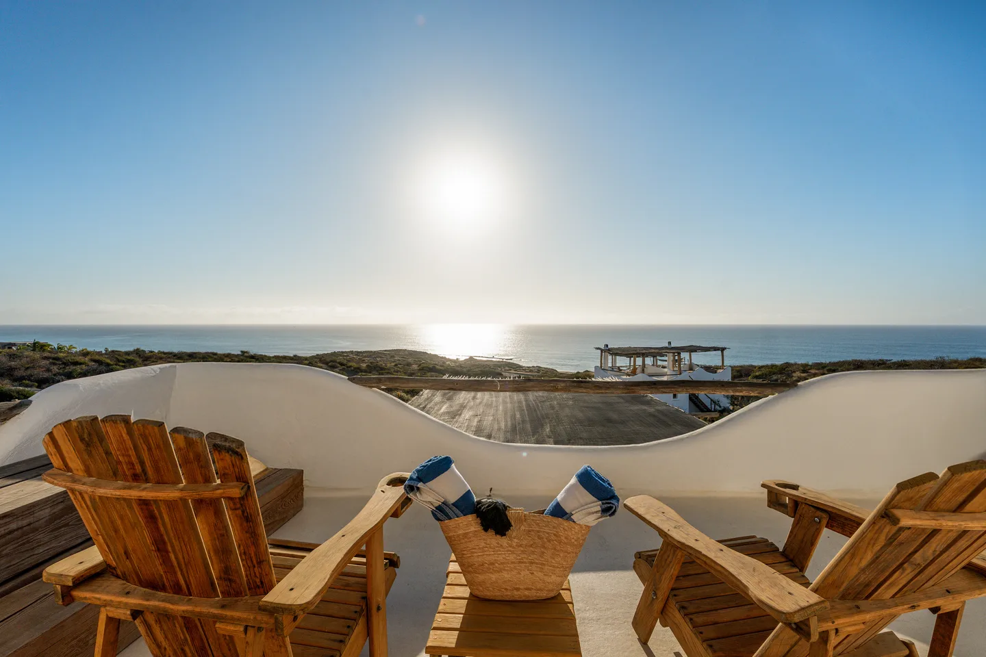 Two wooden chairs on a balcony overlooking the ocean.