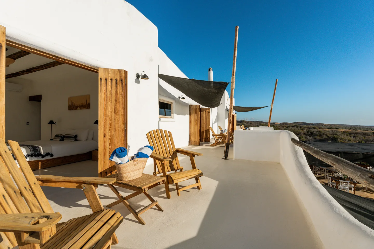 Suite terrace with Adirondack chairs under a deep blue sky — NEST Baja