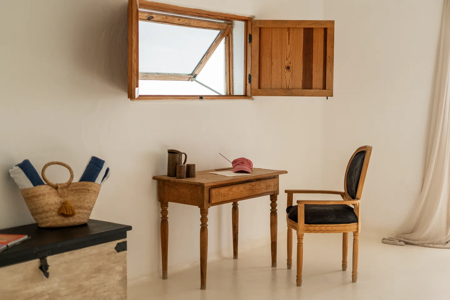 Wooden writing desk beneath a shuttered window — NEST Baja