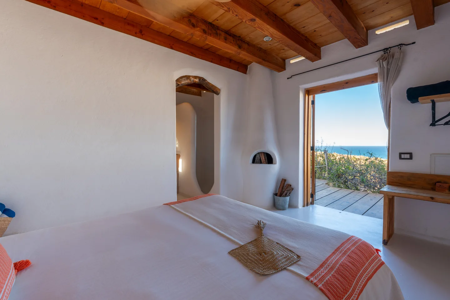 Vista al mar desde la cama a través de puertas de madera abiertas — NEST Baja
